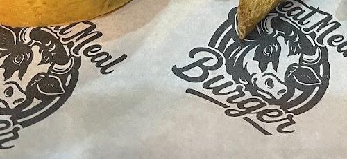 Emblema de toro de Cheat Meal Burger sobre su papel de servicio